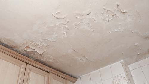 Water-stained ceiling and wall corner showing brown stains
